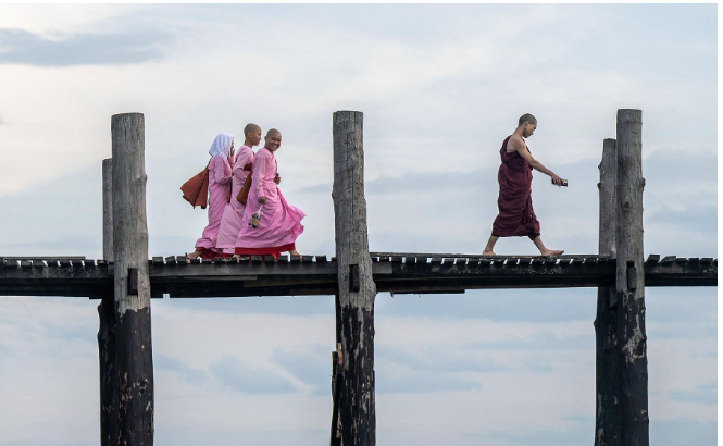 Serene Scene on U Bein Bridge: Buddhist Monk Leads Nuns in Mandalay